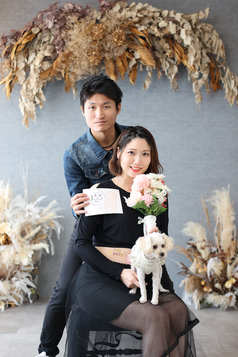 手前に犬、座った女性、後ろに男性が寄り添っている