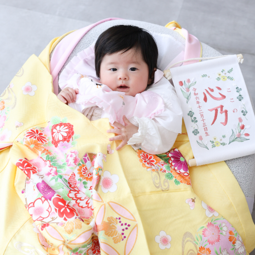 黄色の産着をかけられた赤ちゃん